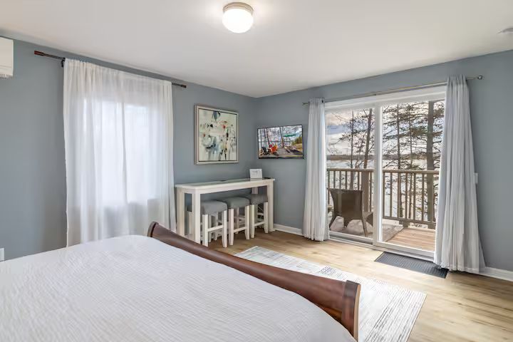 Bright bedroom with white bedding, desk, and sliding glass doors to a balcony.