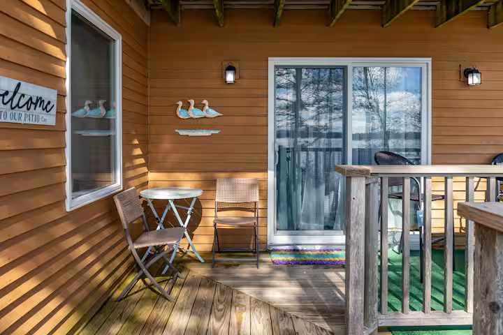 Wooden porch with table and chairs, sliding glass door, and snowy trees outside.