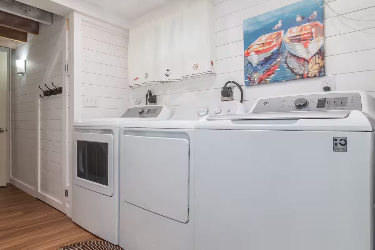 Laundry room with white washer and dryer, white cabinets, and a colorful wall painting