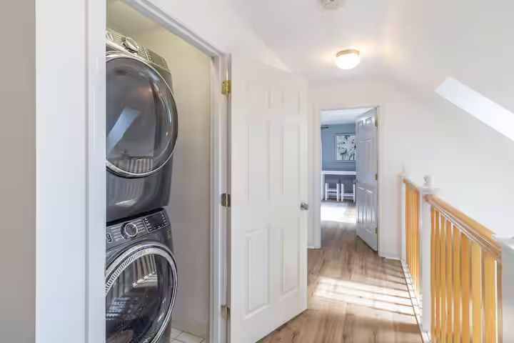 Laundry closet in a bright upstairs hallway with stacked washer and dryer.