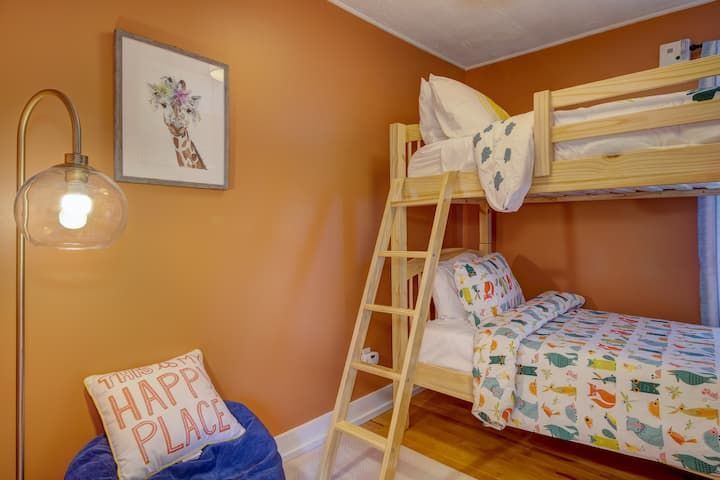 Orange bedroom with bunk bed, ladder, wall art, and a glowing floor lamp