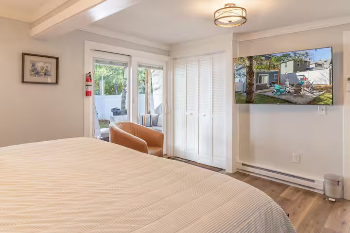 Bright bedroom with bed, white closet, glass doors, and wall art leading to a patio view