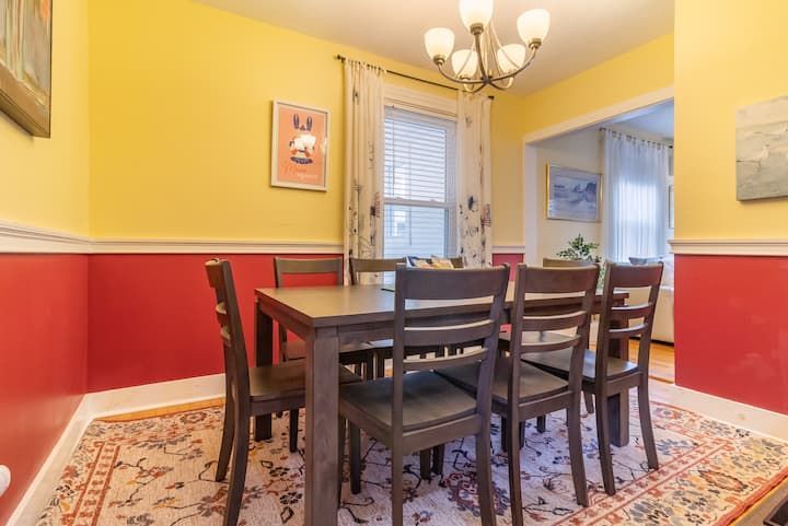 Dining room with yellow walls, red wainscoting, dark wood table and chairs, and a chandelier
