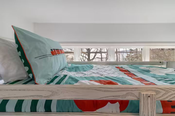 Colorful bed with patterned quilt and pillow in a bright room by a window