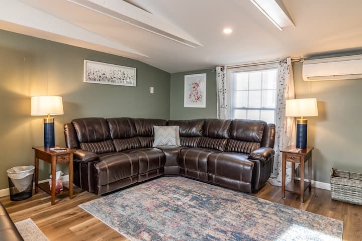 Cozy living room with brown sectional sofa, lamps, wall art, and blue patterned rug