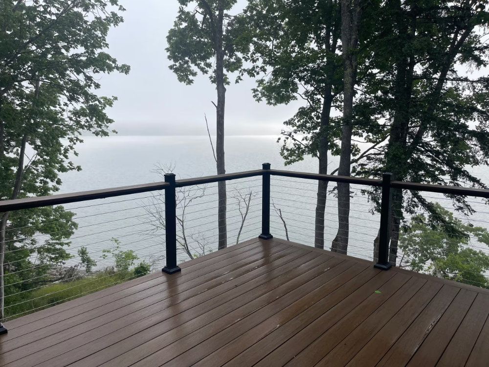 Wooden deck overlooking a calm lake through trees on a misty day