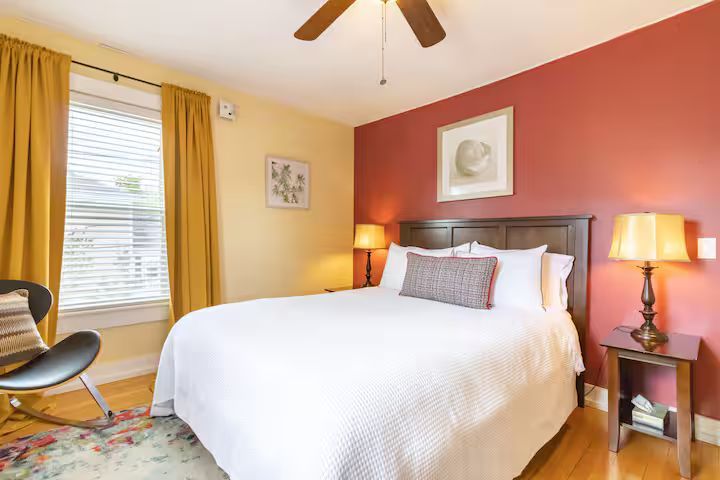 Cozy bedroom with a white bed, coral accent wall, yellow curtains, and bedside lamps