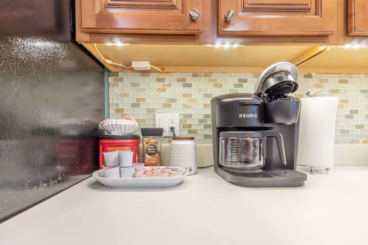 Kitchen countertop with coffee maker, toaster oven, spice jars, and a mug under wooden cabinets
