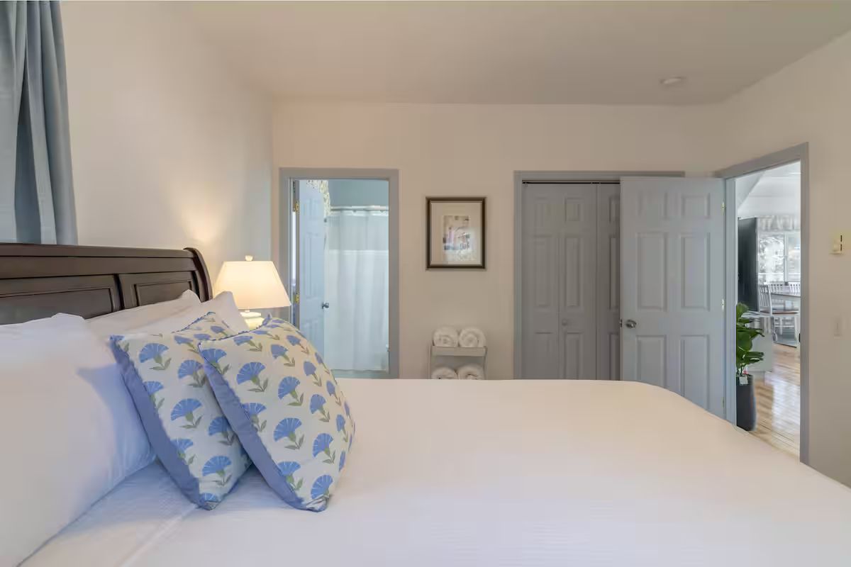 Bright bedroom with a white bed, blue patterned pillows, and an open door to a balcony.