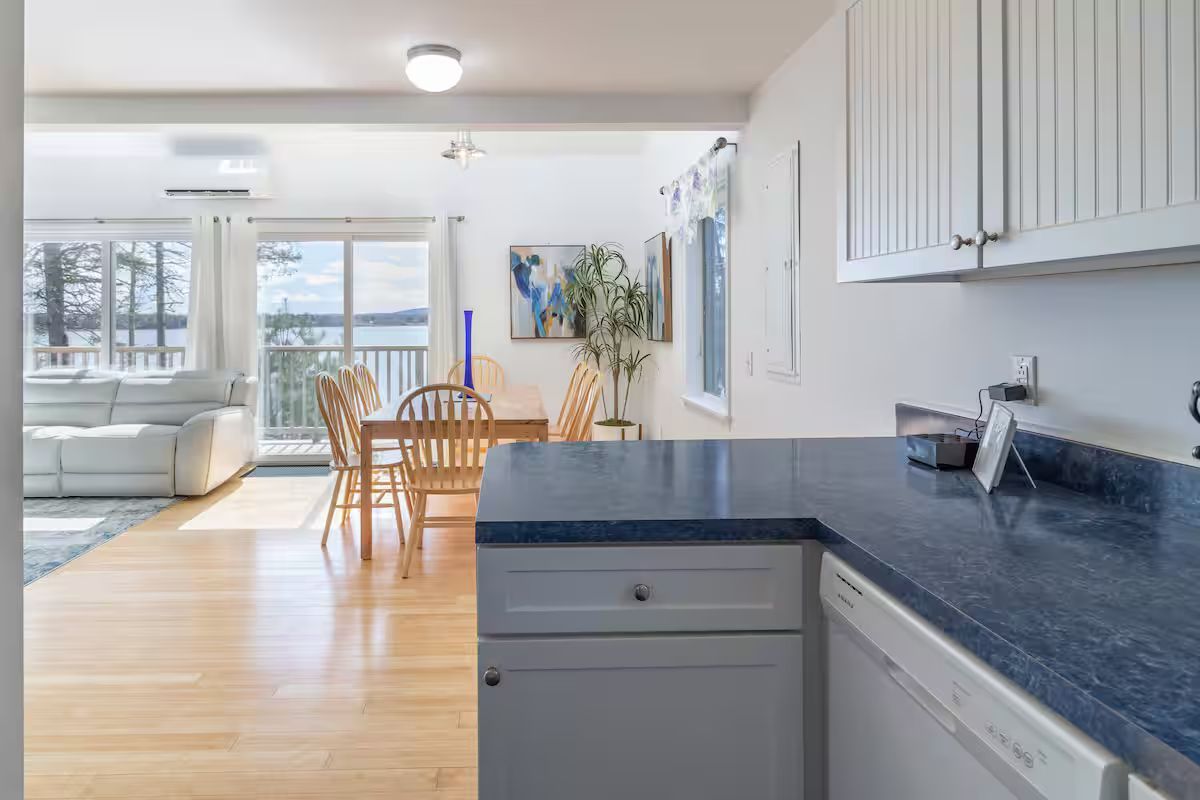 Bright kitchen with blue countertops opening to a sunlit dining and living area.