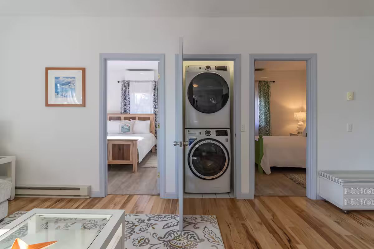 Modern room with stacked washer-dryer between a bedroom and a lit adjoining room