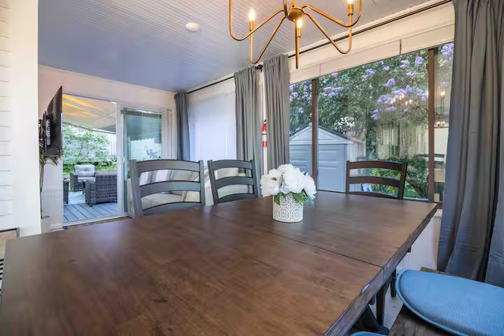 Dining room with wooden table, blue chairs, sliding glass doors, and a view of the patio and trees.