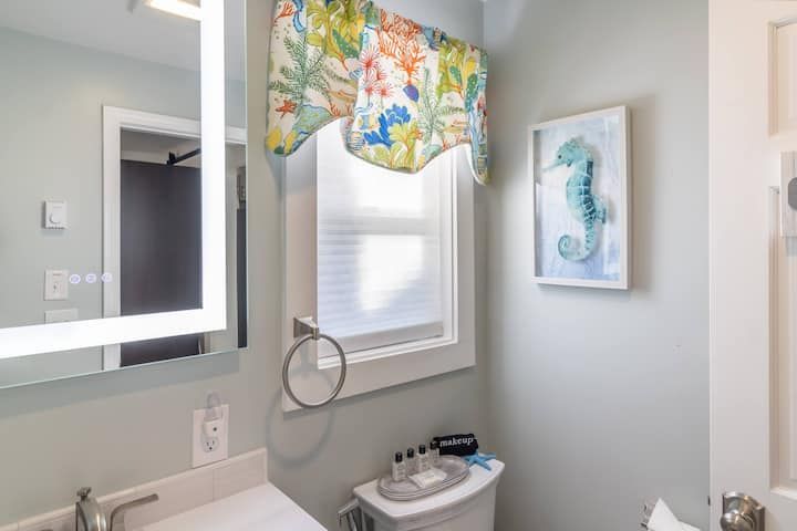 Small bathroom with a sink, mirror, window valance, and framed blue number 3 wall art