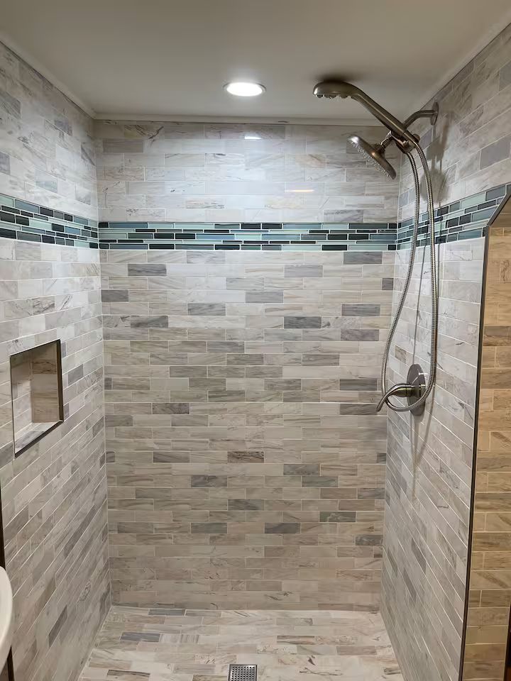 Modern tiled walk-in shower with rain showerhead and handheld sprayer under recessed lighting