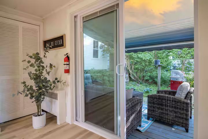 Patio view from a bright room with sliding glass door, wicker chairs, and a potted plant