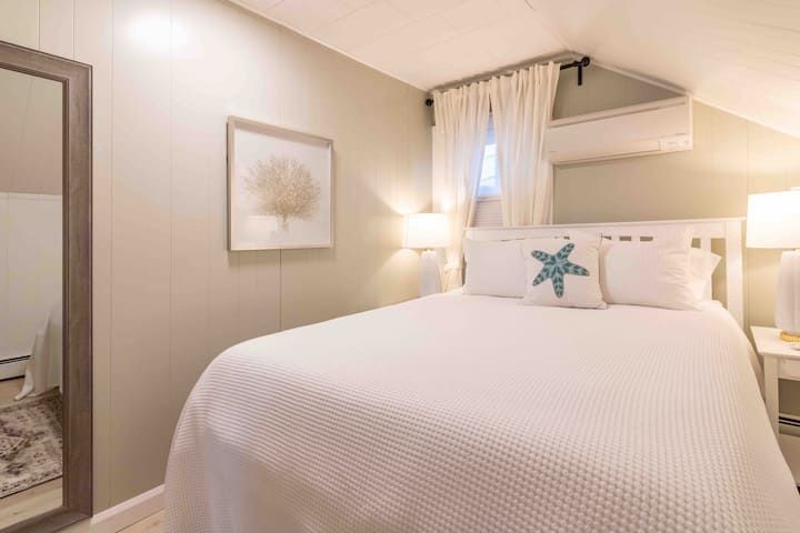 Cozy bedroom with a white bed, soft lighting, and a starfish pillow accent