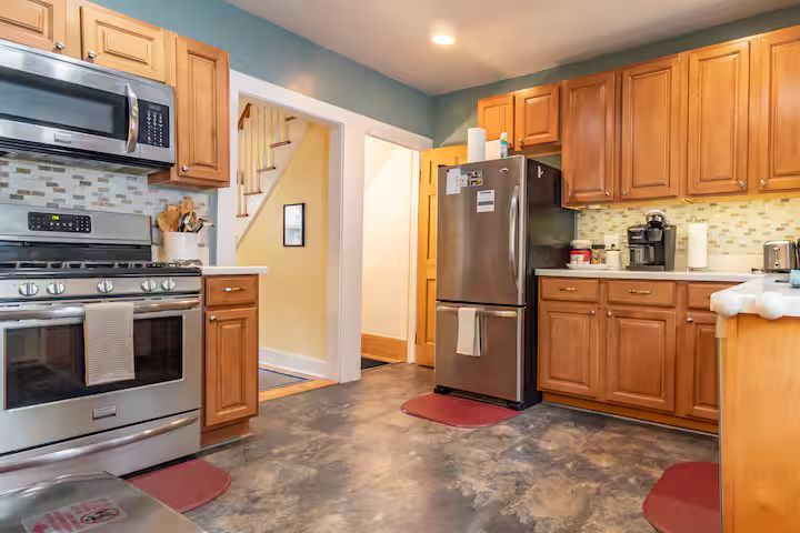 Bright modern kitchen with stainless steel appliances, wood cabinets, and tile flooring