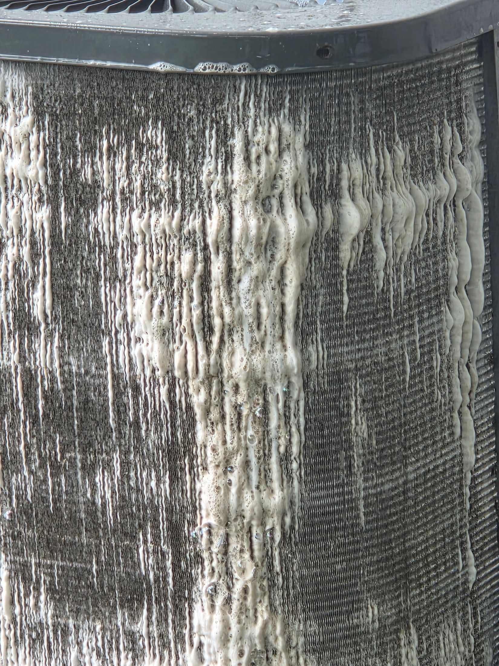 Close-up of a weathered metal surface with vertical streaks of corrosion and grime