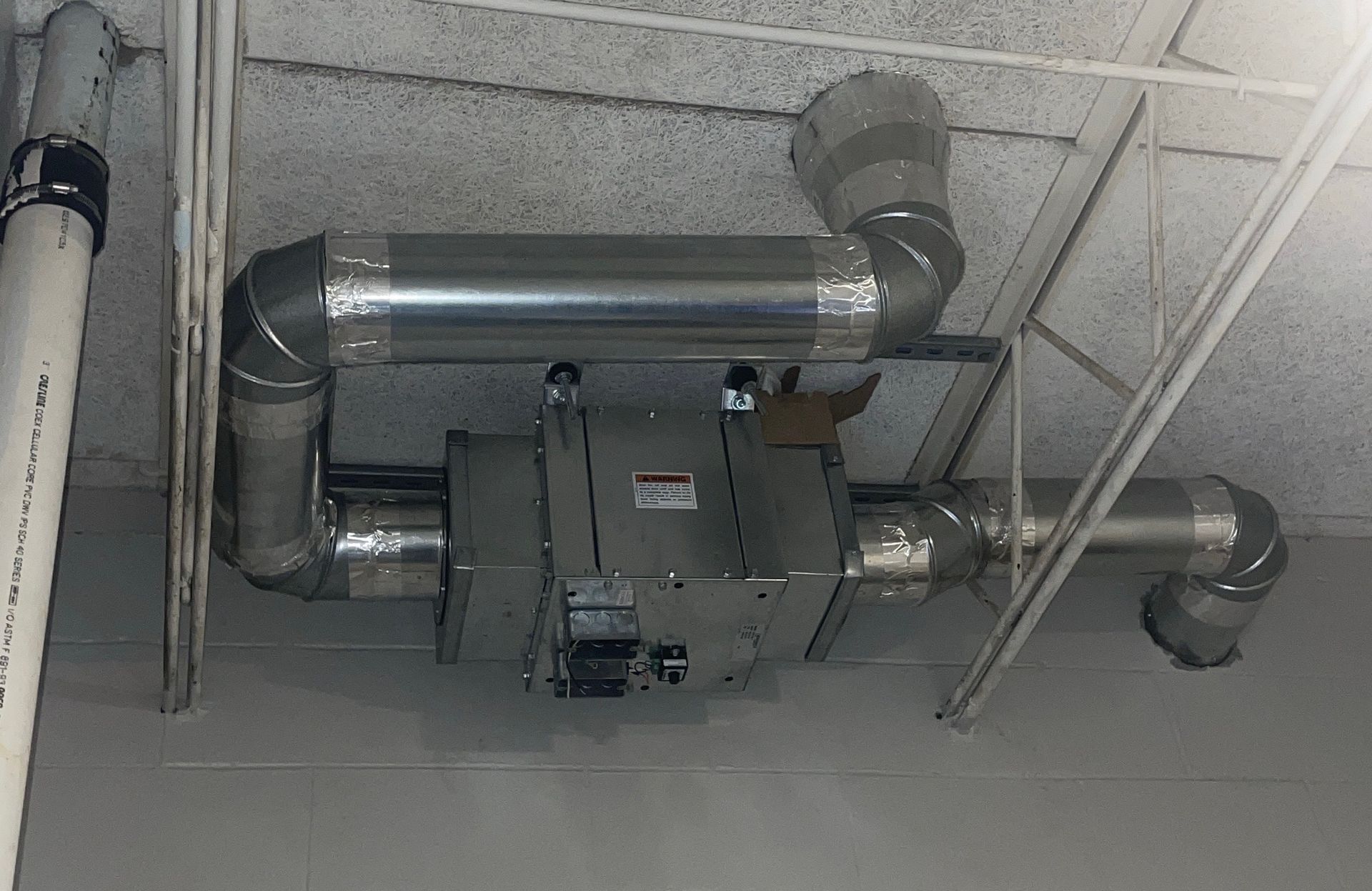 Ceiling-mounted metal HVAC ductwork and equipment in an industrial interior