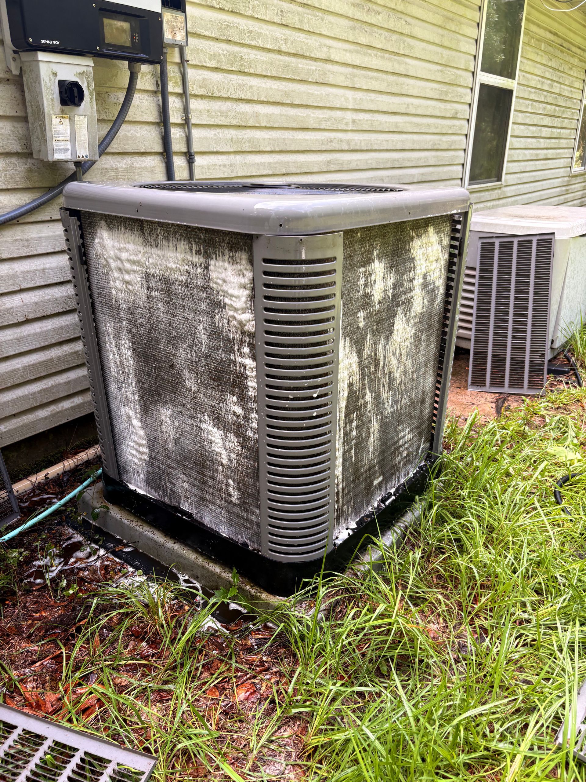 Air conditioning units with toolbox and gloves in backyard.