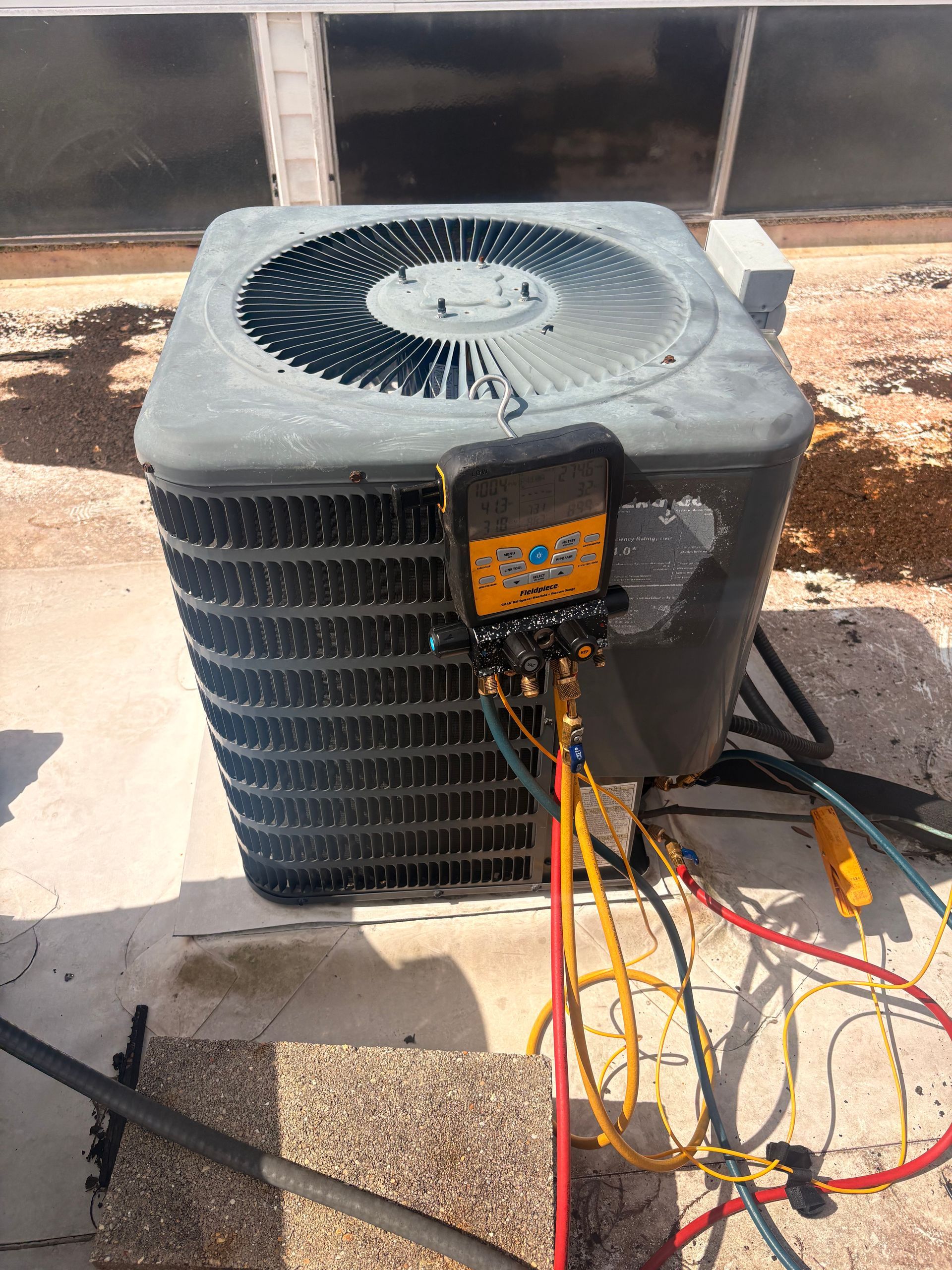 Air conditioning units with toolbox and gloves in backyard.