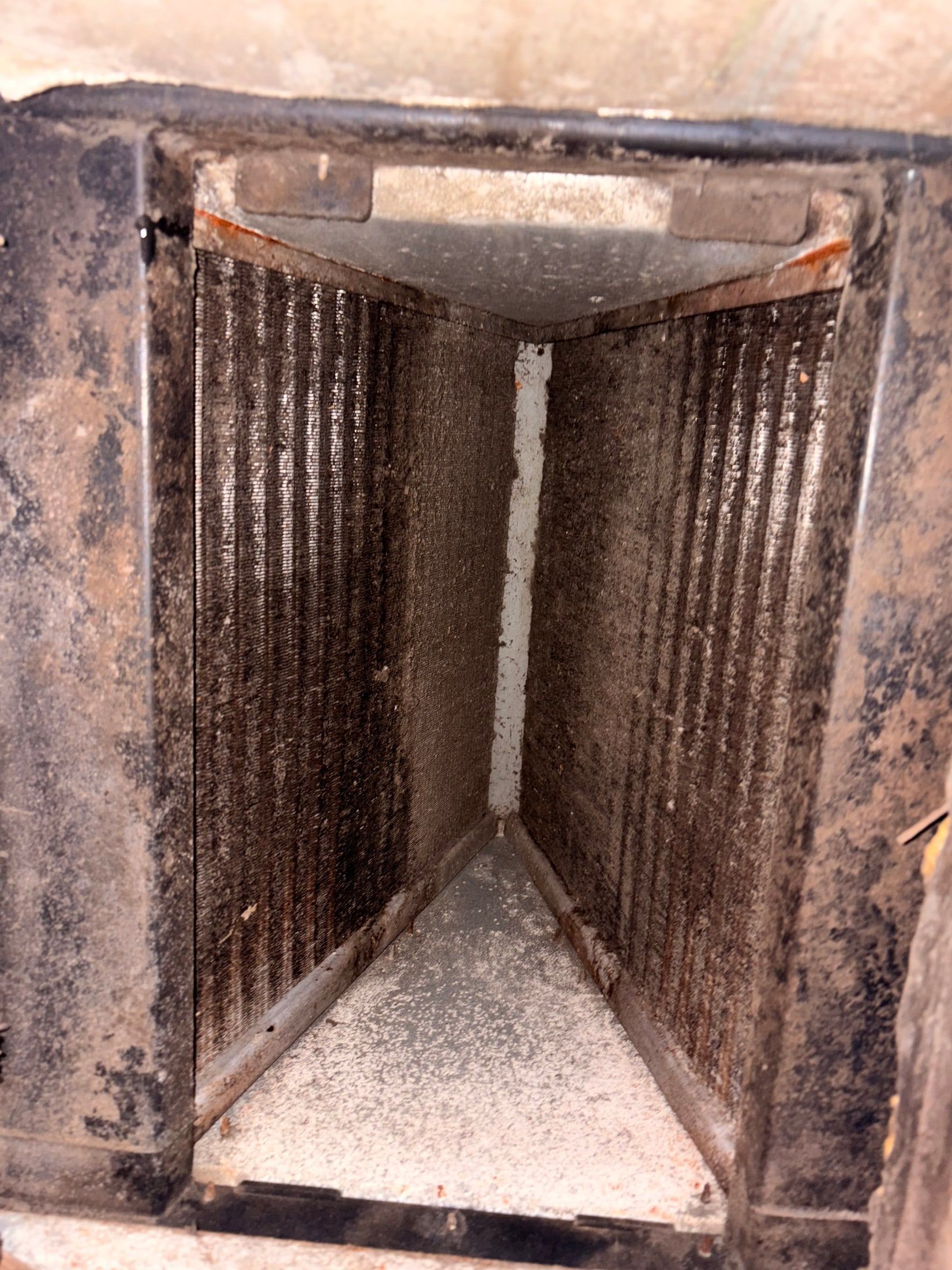 Dusty metal duct or vent with ribbed sides and a triangular floor opening