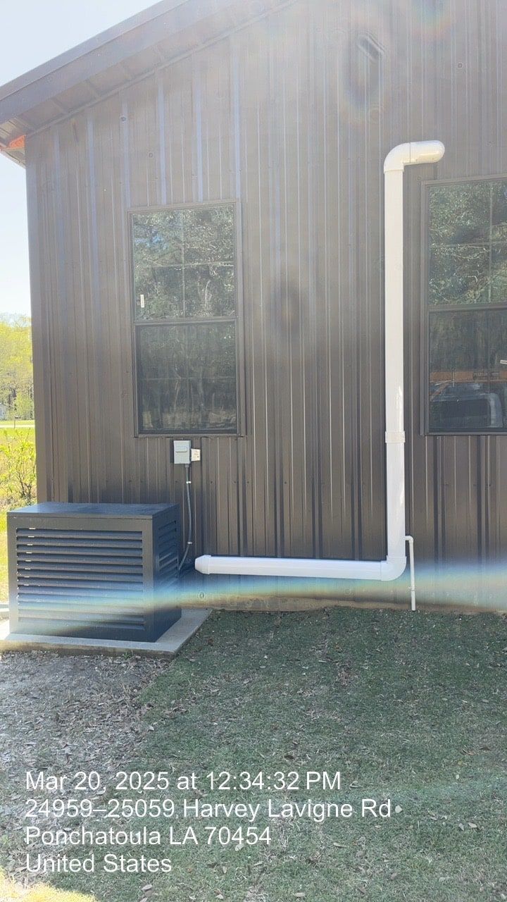 Wood-sided building exterior with a white downspout, two windows, and an AC unit near the ground.