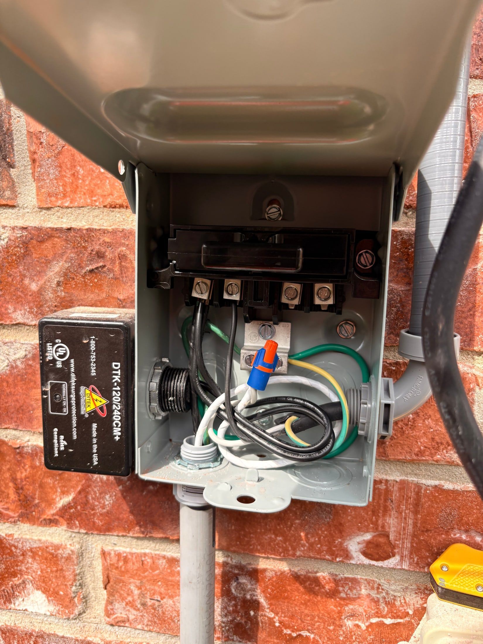 Open electrical junction box on brick wall with exposed wiring and conduit controls
