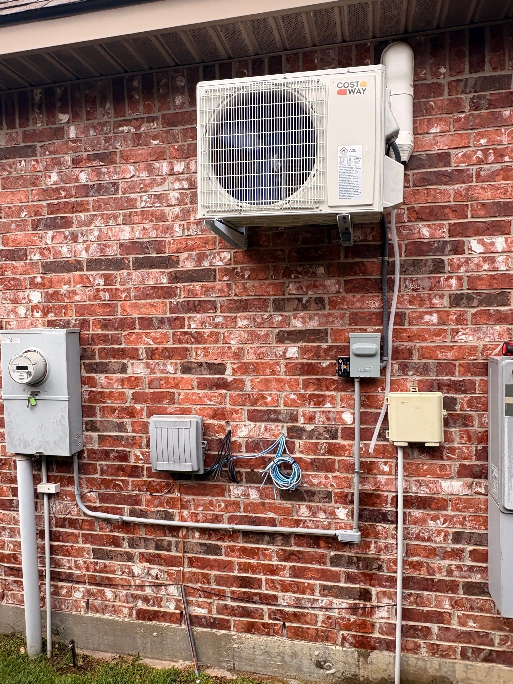 Brick exterior wall with mounted utility boxes, wiring, and a large HVAC unit near the top.