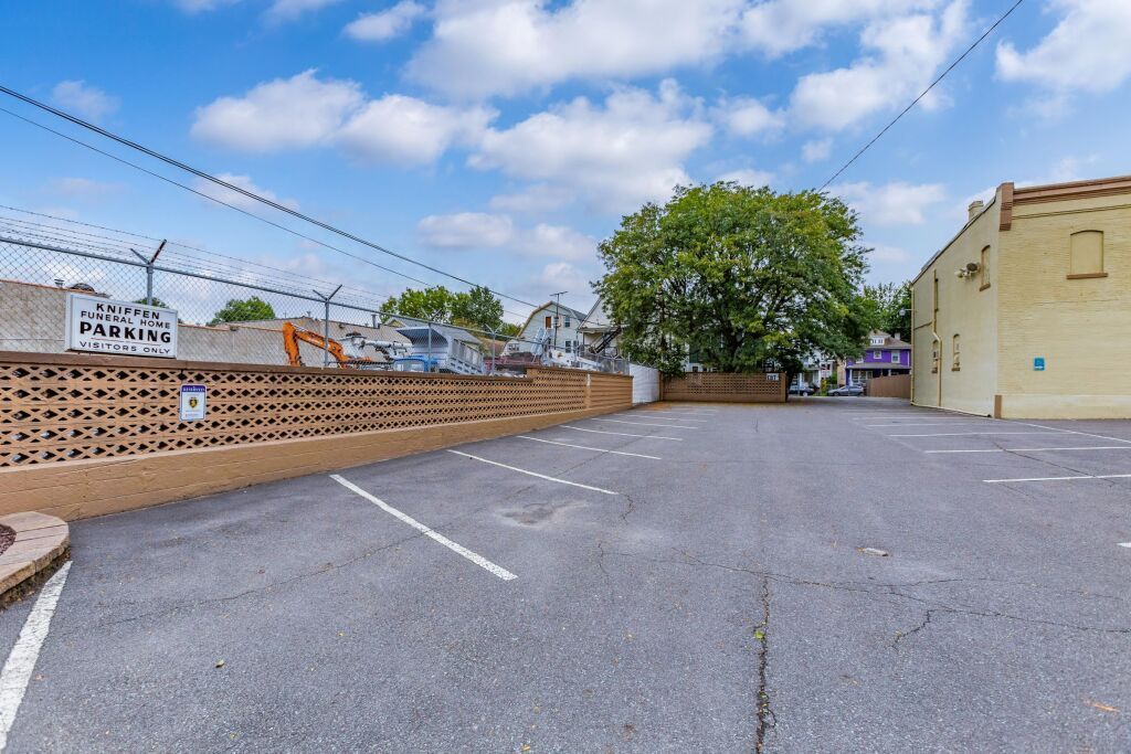 A parking lot with a barbed wire fence and a building in the background.
