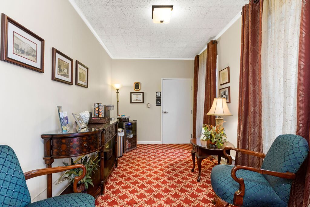 A waiting room with two chairs , a table and a lamp.