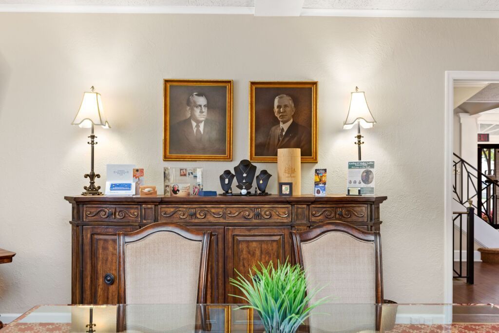A dining room with a table and chairs and two paintings on the wall