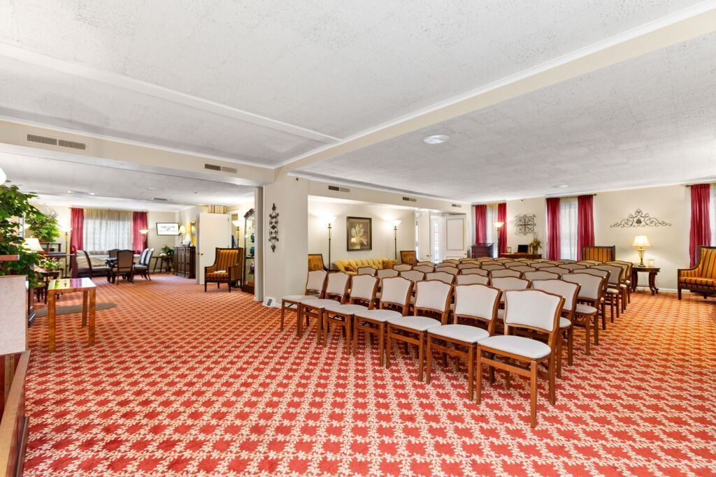 A large room with rows of chairs and a red carpet.