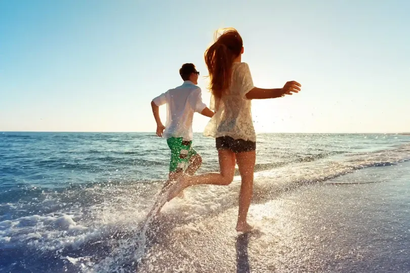 Pareja caminando por la playa en San Andrés, disfrutando del atardecer frente al mar Caribe desde el Hotel Aquamare.