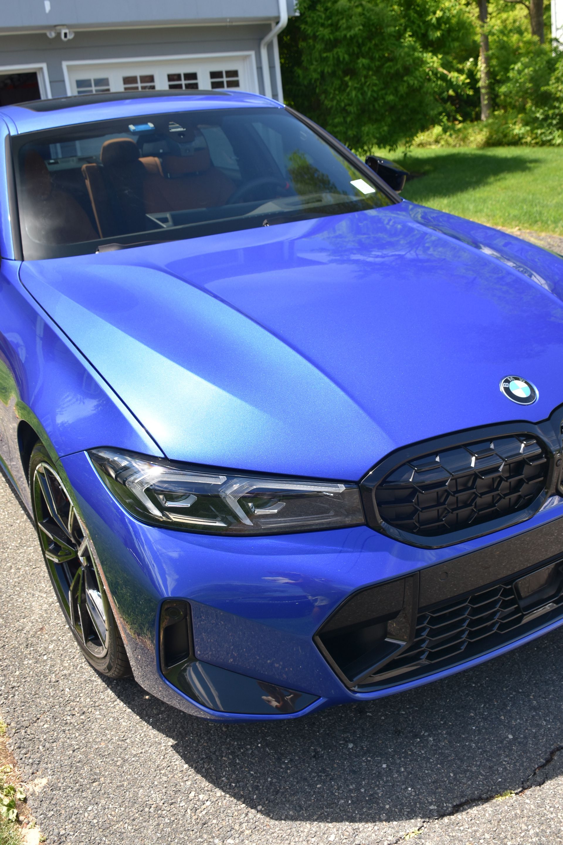Blue BMW sedan parked in a driveway in front of a garage, front view