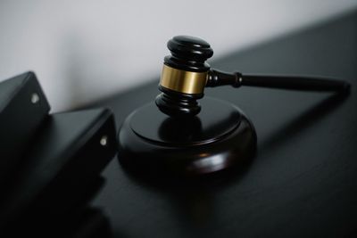 Black judge’s gavel on a dark desk beside a brass sound block