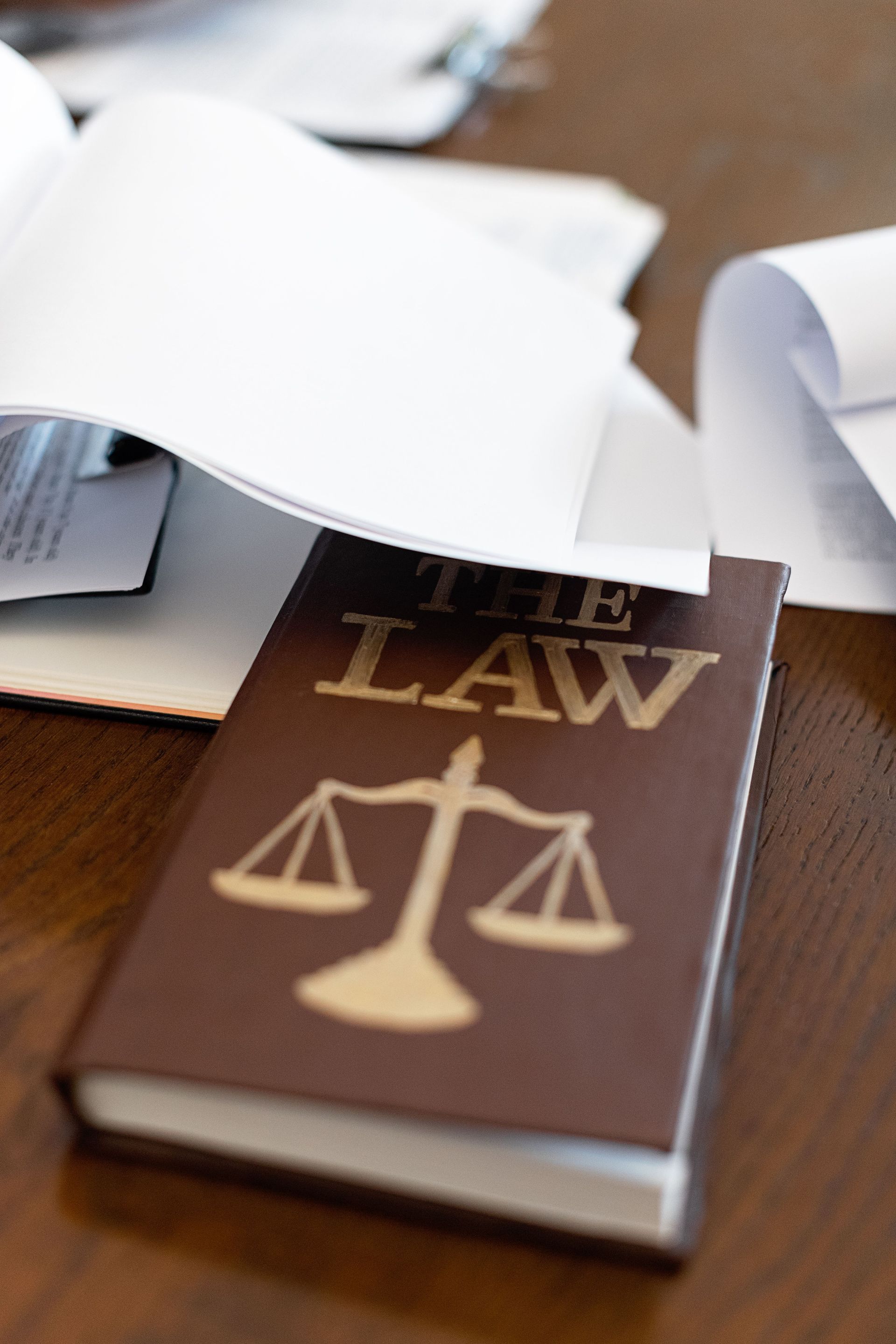 Brown law book with scales symbol under scattered papers on a desk
