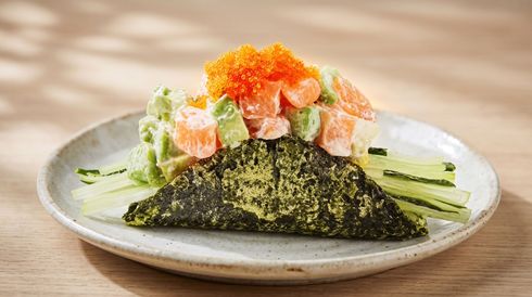 Sushi rice pyramid topped with salmon roe and avocado, served on a white plate with green garnish