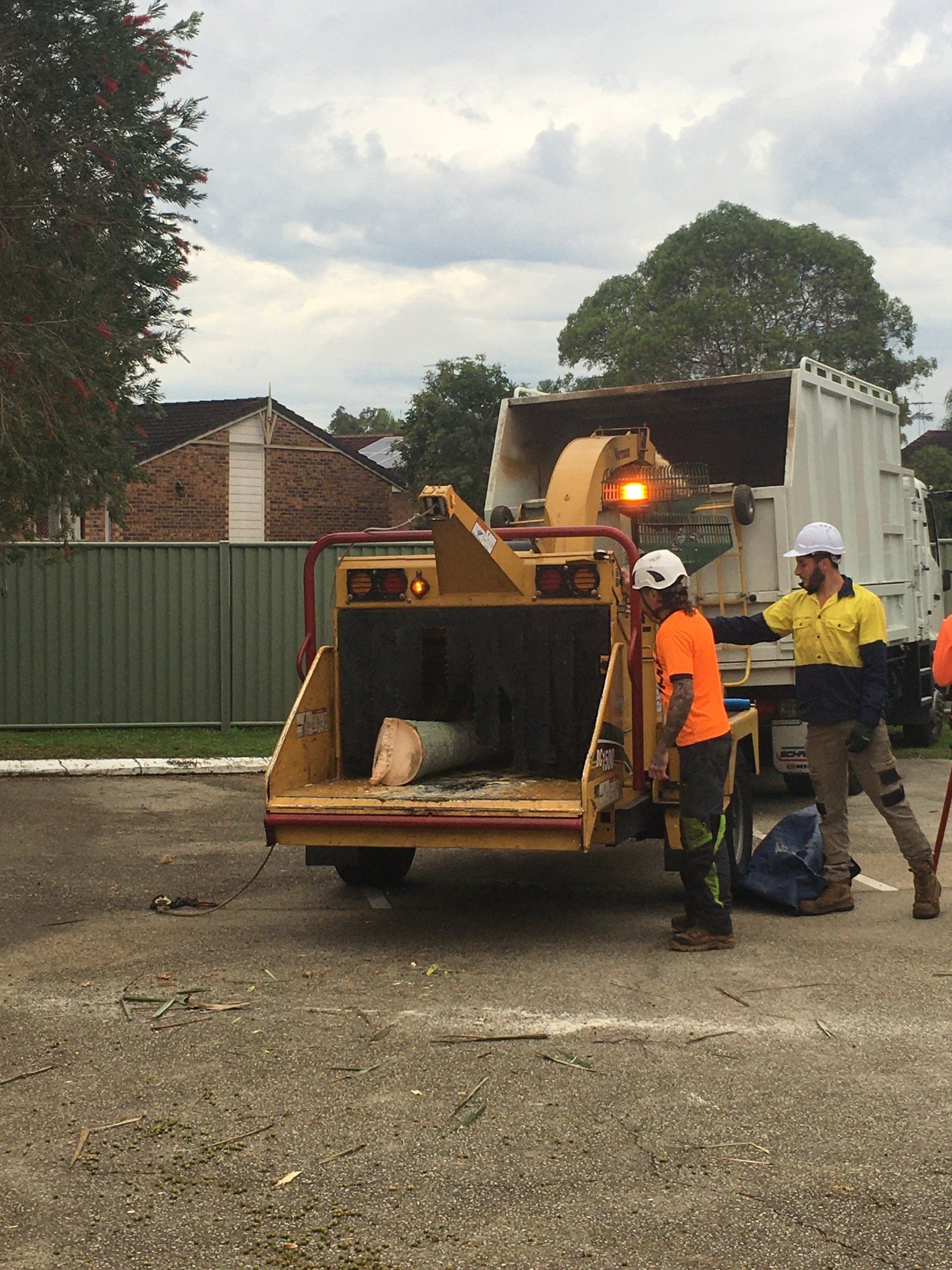 Construction workers beside a yellow skid-steer loader at an outdoor worksite.