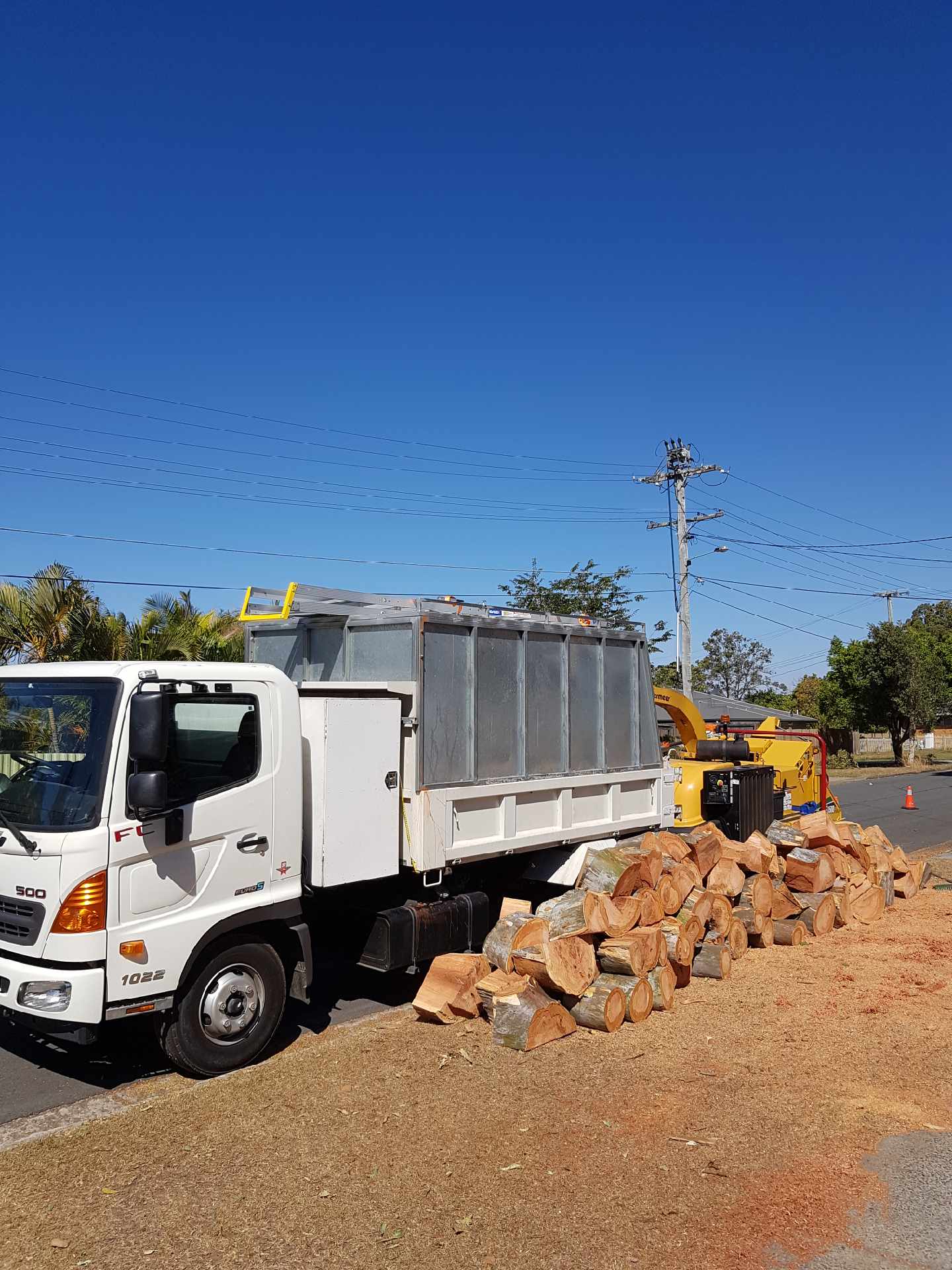 White dump truck beside a pile of broken bricks on a dirt roadside under a clear blue sky