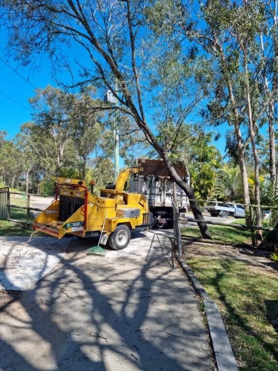 Yellow utility truck with cherry picker parked on a tree-lined residential street near houses