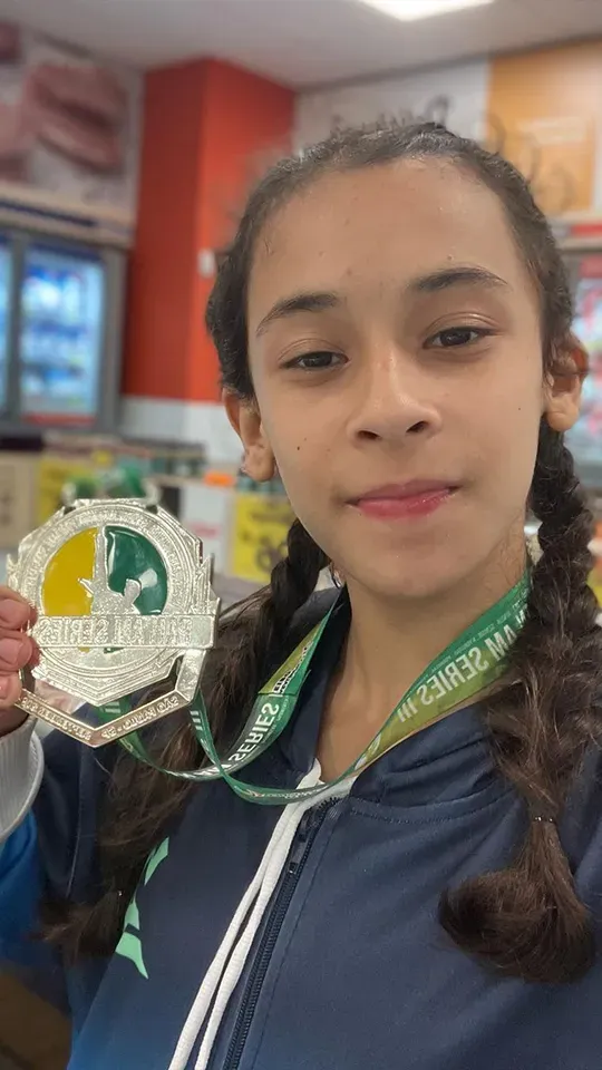 A young girl is holding a medal in her hand.