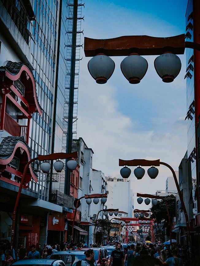 A busy street in a city with lanterns hanging from a pole.