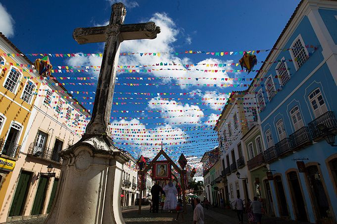 A cross is in the middle of a street surrounded by buildings.