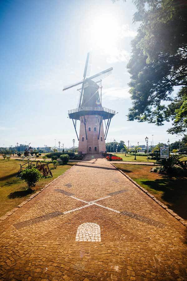 There is a windmill in the middle of a park.