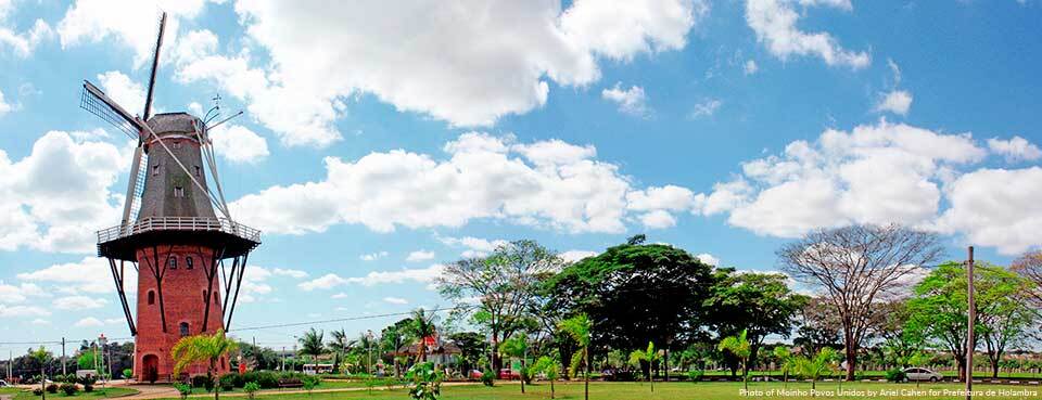 A windmill in a park with a blue sky and clouds in the background