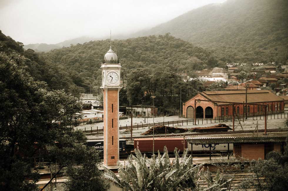 A clock tower in the middle of a city with mountains in the background