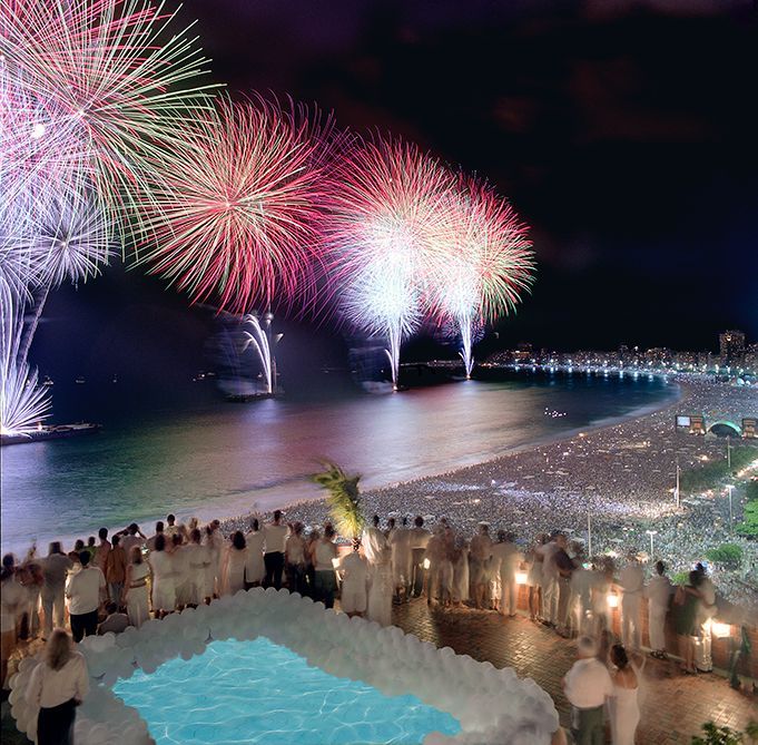 A group of people are watching fireworks over the ocean.