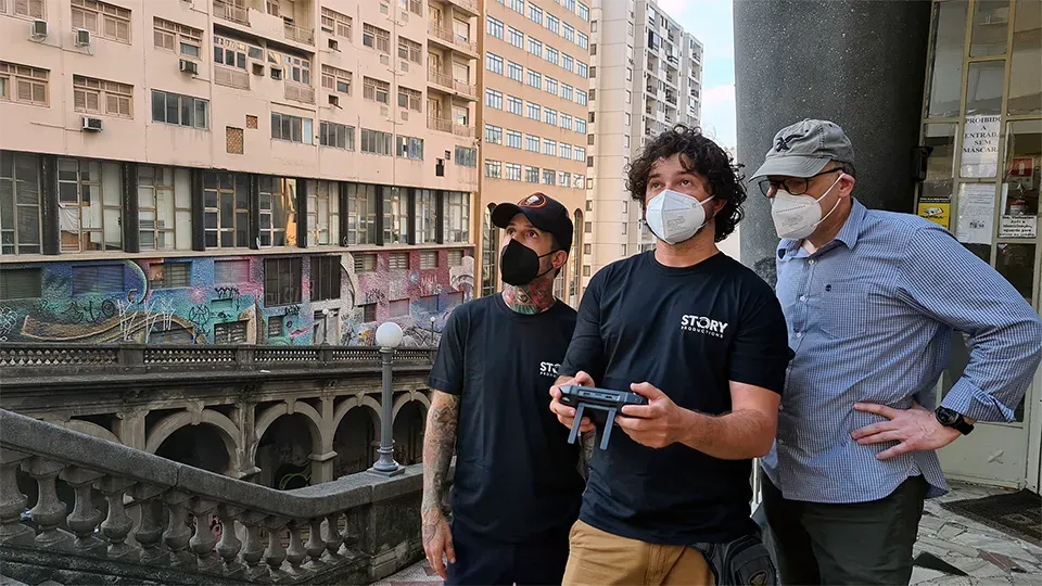 Three men wearing face masks are standing next to each other in front of a building.
