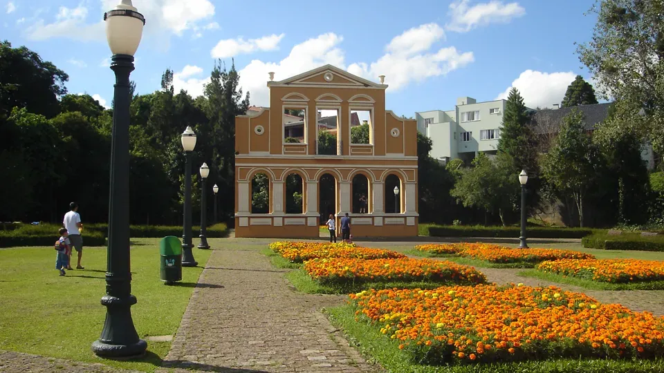 A large building in a park with flowers in front of it